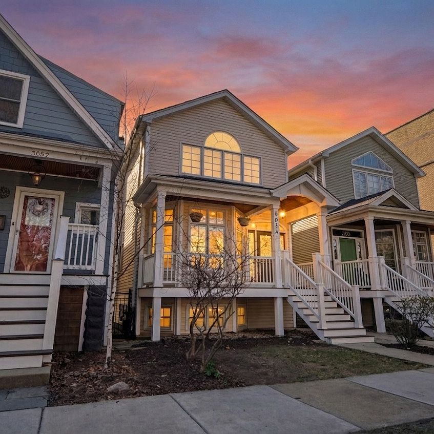 Front elevation of 5054 N Claremont Avenue at dusk, a three-story Chicago single family home with a covered front porch, arched second-story window, and a vivid pink and orange sunset sky above the rooftops